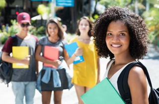 Young woman holding a binder with her fellow students standing behind her.