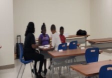 Students sitting with a female teacher.