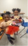 Two girls holding teddy bears.