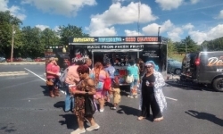 People are waiting in front of a drink truck.