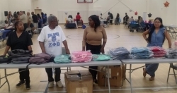 Several adults are ready to hand out backpacks.