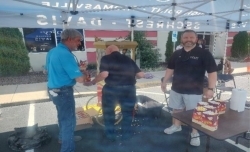 Three men making and handing out bags of popcorn.