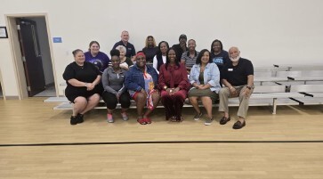 A group of fourteen people sitting and smiling for a photo at the home buyers workshop.