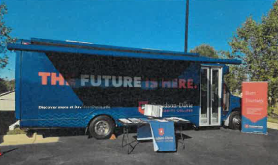 Bus with a display table and banner with the text, The Future is Here.