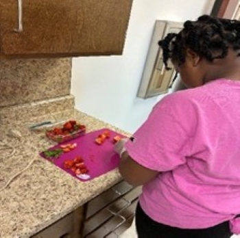 Girl cutting up strawberries.
