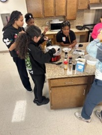 Group of young residents getting soup from a crockpot.