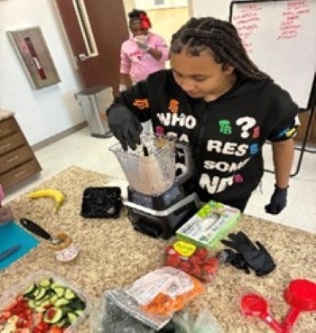 Loung lady adding fruits and vegetables to the smoothies.