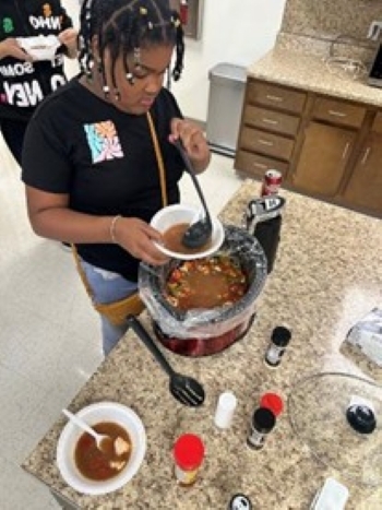 Young lady filling a bowl with soup from a crockpot.