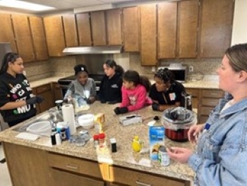 Youth residents of THA during a cooking lesson with a woman from AmeriHealth.