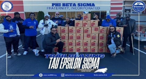 A group of people standing by boxes of food.