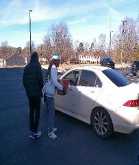 Two people standing by the drivers door of a car.
