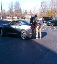 Two people standing by the trunk of a car.