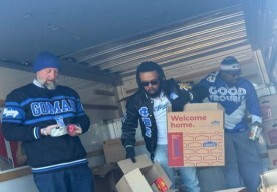 Three men unloading boxes of food out of a truck.