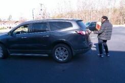 A man standing behind an SUV.