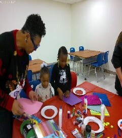 A woman helping little kids with arts and crafts.