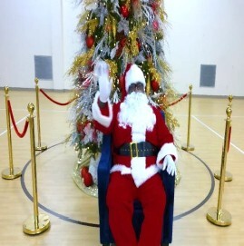 Santa waving with a tree behind him.