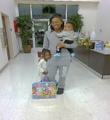 A woman holding two kids and a gift.