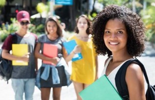 A girl smiling in the foreground, with three other students behind her.