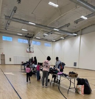 A zoomed out view of people walking around a table of clothes.