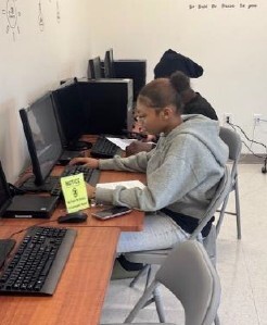 A girl sitting at a computer looking up information.