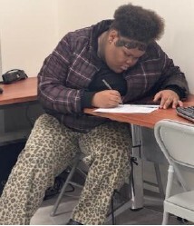 A girl sitting at a desk writing.