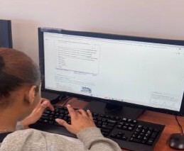 Looking over a young girls shoulders as she's typing on a computer.
