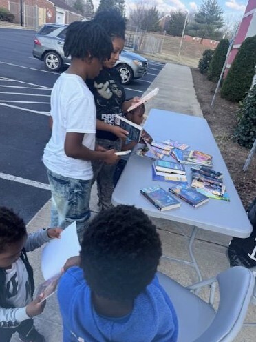 Four young children looking at books on a table