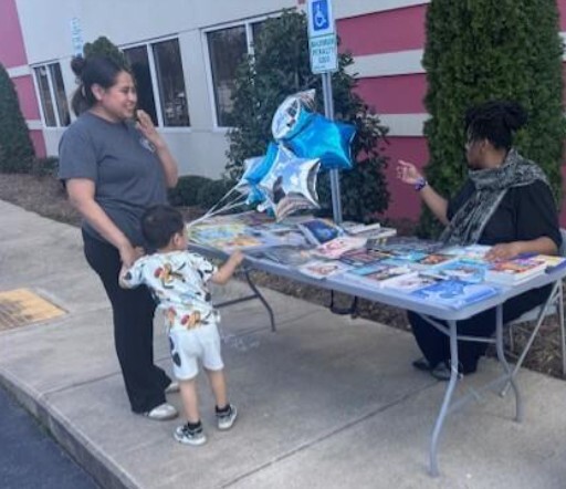 A woman and a child look at books on a table.