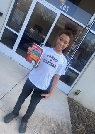 A child smiling holding a book. 