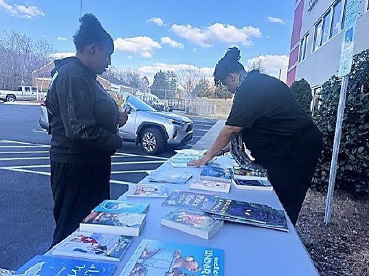 A young girl and a woman look at books.