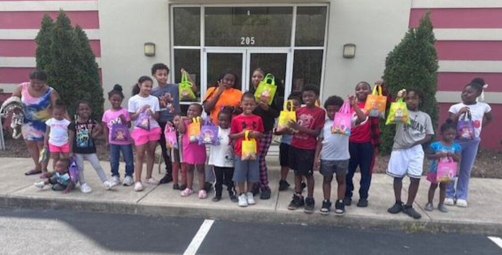 A group of people outside the Lois. A Hunter Life Skills Center holding gift bags.