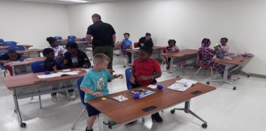 Kids sitting at tables doing activities.