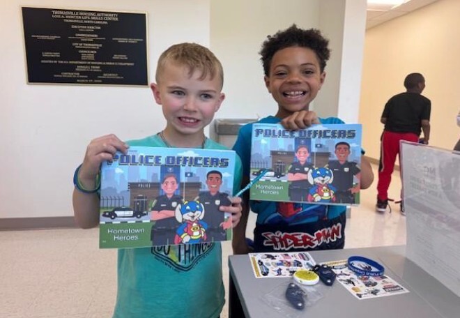 Two young boys holding up police officer books.