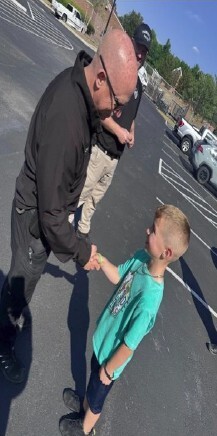 A police officer shakes hands with a young boy.