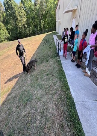 A police officer walking his k9 dog around kids.
