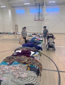 Two people looking at tables of clothes.