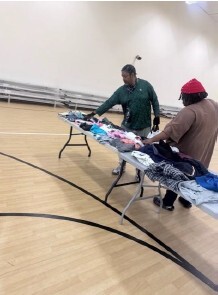 Two men looking at clothes on tables.