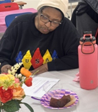 A woman sitting at a table, filling out paperwork.