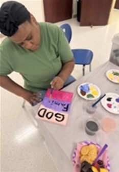 A woman sitting at a table painting.