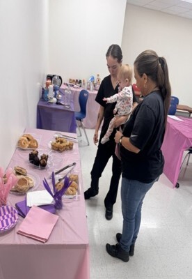 Two women and a child stand by a table with donuts on it.