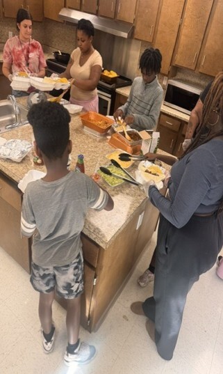 Five people making tacos in a kitchen.