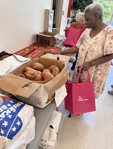 A woman looking at a box of sweet potatoes.