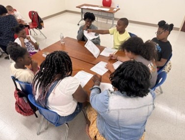 Kids sitting around a table looking at papers.