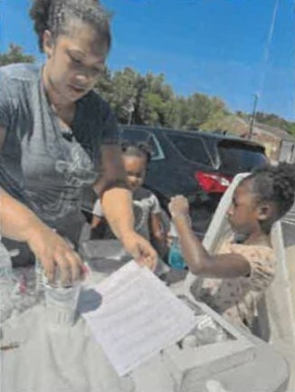 A woman helping two young kids with making a solar oven. 