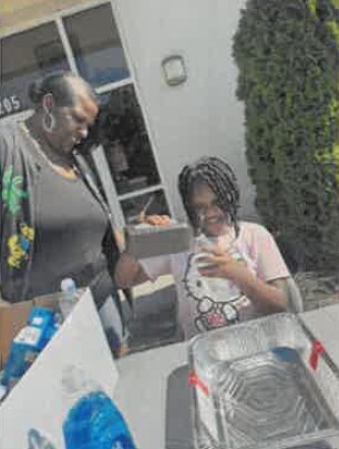 A woman helping a young girl with her solar smore oven.