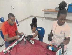 A man helping two young girls with a project at a table.