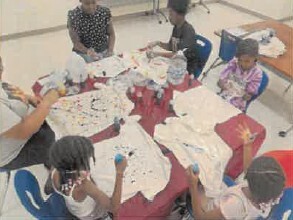 Multiple people doing art projects at a table.