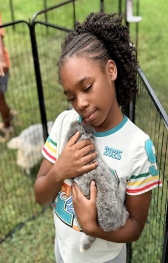 A girl holding and hugging a bunny rabbit.