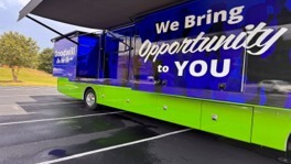 A blue and green bus with the words We Bring Opportunity to You on the side of it.