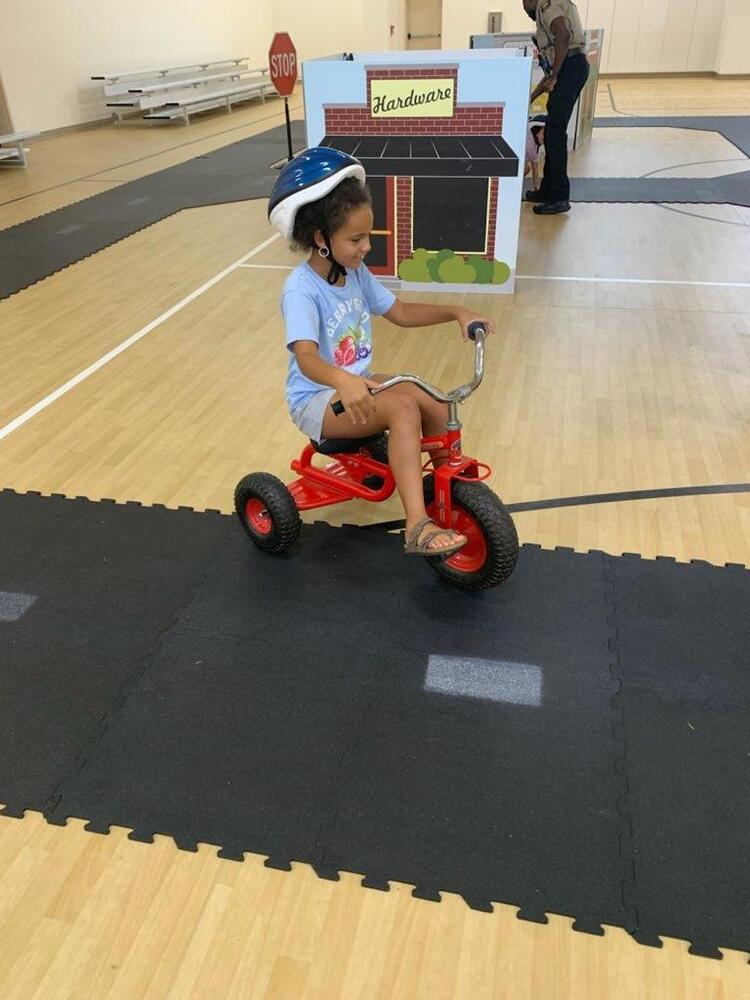 A girl rides a tricycle in a gym.